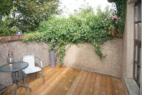a patio with a table and chairs and flowers on a wall at The Garrandarragh Inn in Mullinavat