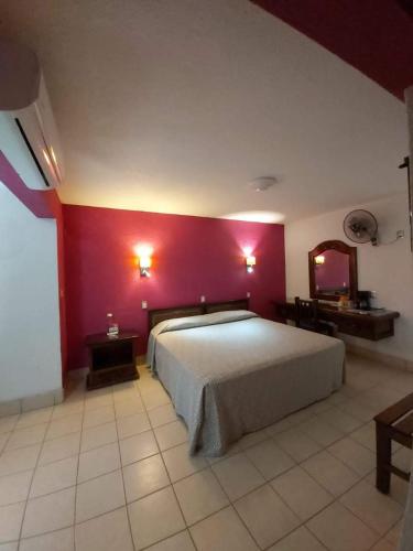 a bedroom with a large bed and a red wall at Hotel Aurora in Oaxaca City