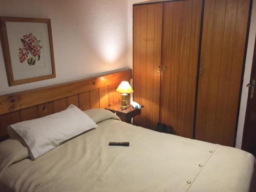 Un dormitorio con una cama blanca y una lámpara en una mesa en Departamento en Cerro Catedral en San Carlos de Bariloche