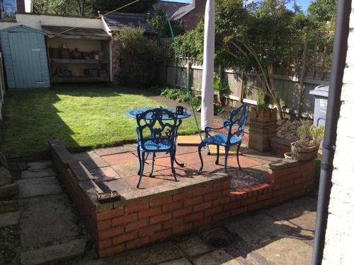 マックルズフィールドにあるLa casa de Eloisaの庭に青い椅子2脚とテーブル1台