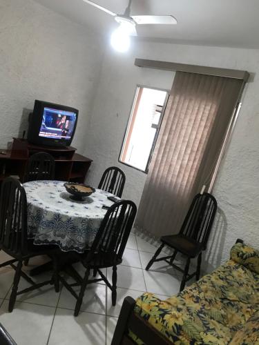 a dining room with a table and chairs and a television at Edifício Marambaia in Praia Grande