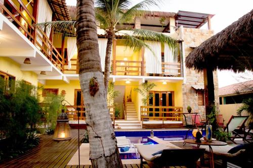 un complexe avec un palmier et une piscine dans l'établissement Villa Água de Coco, à Jericoacoara