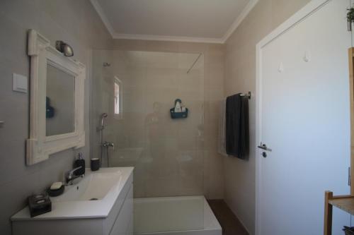 a white bathroom with a sink and a shower at Number 10 Beach House in A dos Cunhados