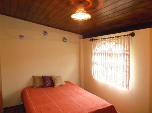 1 dormitorio con cama y ventana en Chalé Barra Velha, en Ilhabela
