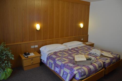 a hotel room with a bed with a book on it at Hotel Ladina in Campitello di Fassa