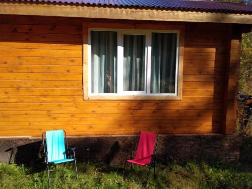 リストヴャンカにあるBaykalskaya Taiga Guesthouseの窓のある家の前の椅子2脚