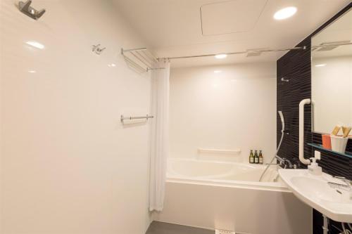 a white bathroom with a tub and a sink at M's Hotel Kyoto Station Taruya in Kyoto