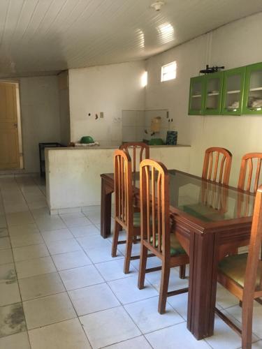 a dining room with a table and chairs and a kitchen at Hostel Manga Rosa in Santarém