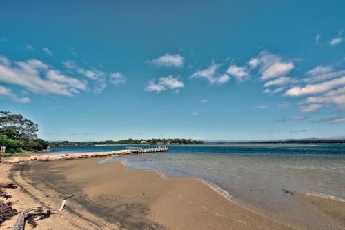 a sandy beach with a pier in the water at Containment Accommodation in Coles Bay