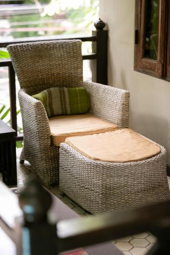 a wicker chair with a pillow on a porch at Amata Lanna Chiang Mai, One Member of the Secret Retreats in Chiang Mai