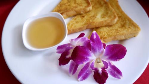 a plate with toast and a purple flower and a cup of sauce at Phi Phi Maiyada Resort in Phi Phi Don