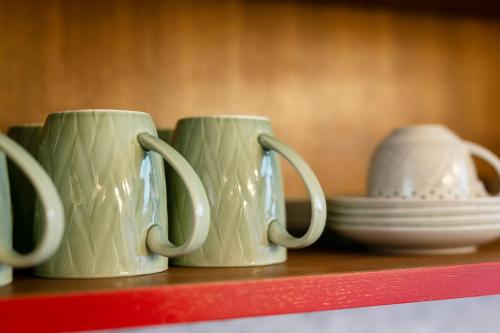 three coffee mugs sitting on a shelf with plates at Amata Lanna Chiang Mai, One Member of the Secret Retreats in Chiang Mai