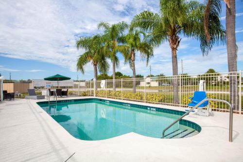 una piscina con una silla azul y palmeras en Howard Johnson by Wyndham Vero Beach/I-95, en Vero Beach
