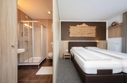 um quarto com uma cama grande e um chuveiro em Fairhotel Hochfilzen B&B em Hochfilzen