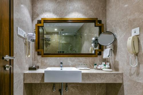 a bathroom with a sink and a mirror at Sun-n-Sand Shirdi in Shirdi