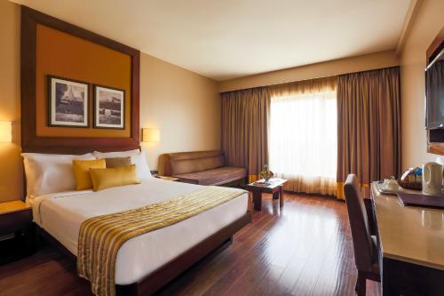 a hotel room with a large bed and a desk at Sun-n-Sand Shirdi in Shirdi