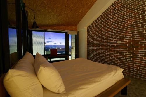 a bed sitting in front of a window next to a wall at OwlStay Jiufen Wander in Jiufen