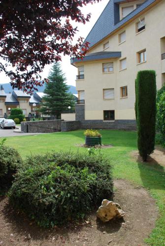 a large building with a green yard in front of it at Atico en Biescas con Piscina, Tenis y Barbacoa in Biescas