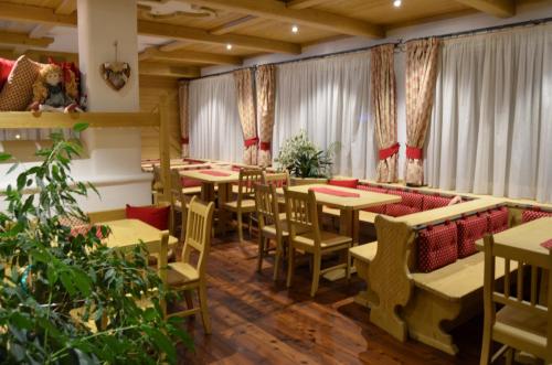 un restaurante con mesas, sillas y cortinas en Hotel Ladina, en Campitello di Fassa