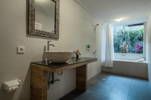 ein Badezimmer mit Waschbecken und Spiegel in der Unterkunft Taman Harum Cottages in Ubud