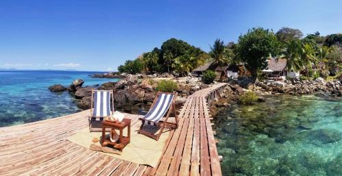 a wooden deck with two chairs and the water at Remo e Berenice in Nosy Komba