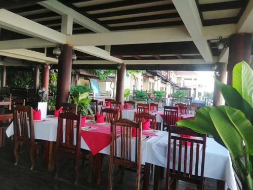 un restaurante con mesas y sillas con servilletas rojas en Pon Arena Hotel, en Muang Không