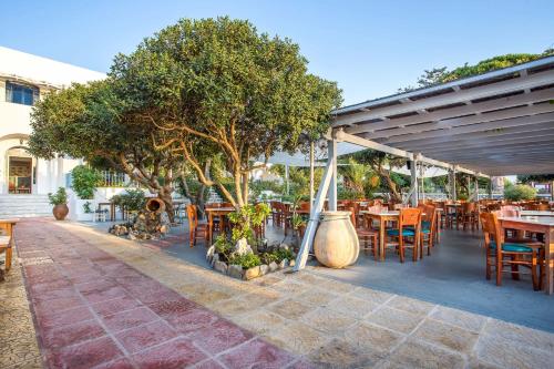 un ristorante con tavoli e sedie in legno e alberi di Alinda Hotel ad Alinda