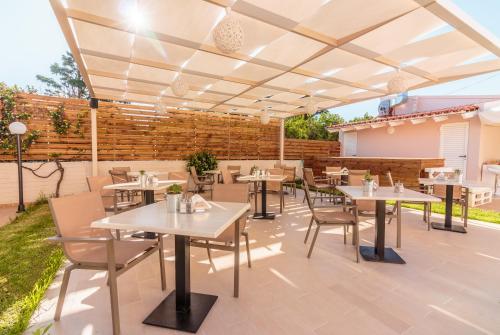 a patio with tables and chairs under a pavilion at Evdokia Αpartments & Dimitra Village in Agia Marina Nea Kydonias