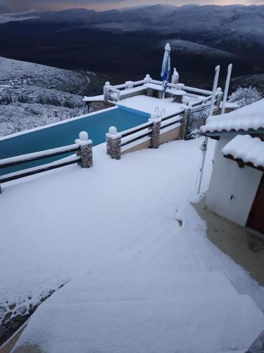 a house covered in snow next to a fence at ZenTerra Country house with prive swimming pool and view in Matésion