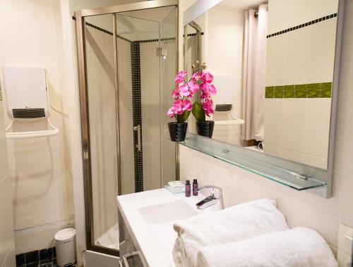 La salle de bains est pourvue d'un lavabo, d'un miroir et de fleurs. dans l'établissement pause café avec sauna, à Annecy