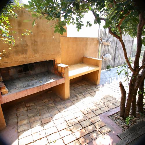 a wooden bench sitting on a patio under a tree at Tree House Villa in Praia do Tofo