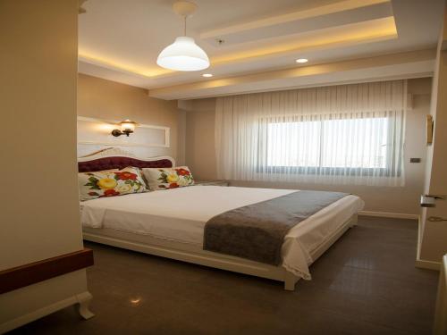 Schlafzimmer mit einem großen Bett und einem Fenster in der Unterkunft Lion Park Suites & Residence Hotel in Aydın