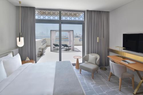 a hotel room with a bed and a desk and a television at Vida Creek Harbour in Dubai