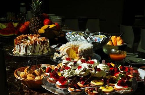 ein Tisch mit Tellern voller Essen und Desserts in der Unterkunft Petry Plaza Hotel in Canoinhas