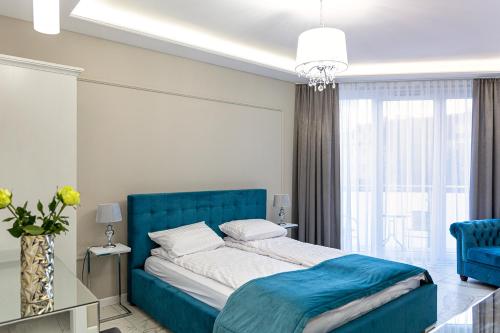 a bedroom with a blue bed and a large window at Apartamenty Prestiż 93 in Koszalin