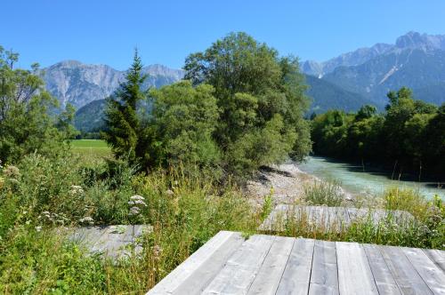 a wooden bridge over a river with mountains in the background at Hotel Saliter Hof in Saalfelden am Steinernen Meer