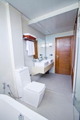 a white bathroom with a toilet and a sink at Dreams Grand in Hulhumale
