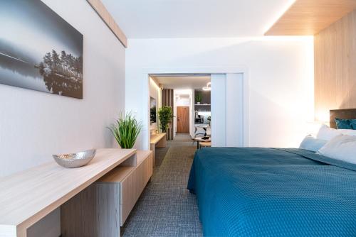 Un dormitorio con una cama azul y un escritorio de madera. en Apartman Pod Hrebienkom - C218, en Starý Smokovec