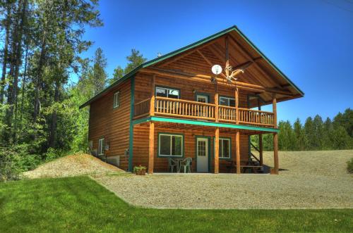 a log cabin with a balcony and a deck at Paddle Ridge in West Glacier