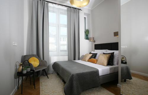 a bedroom with a bed and a chair and a window at Gem Apartment by Castle (Old Town Krakow) in Krakow