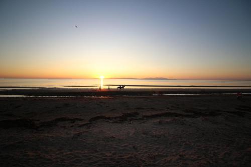 a sunset on the beach with people walking on the beach at Burnside Guest House in Ayr