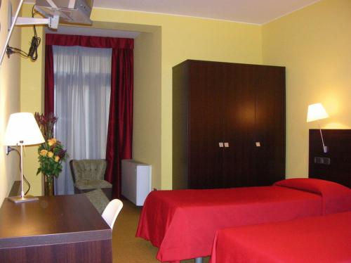 una camera d'albergo con due letti, un tavolo e una sedia di Albergo Verdi a Padova