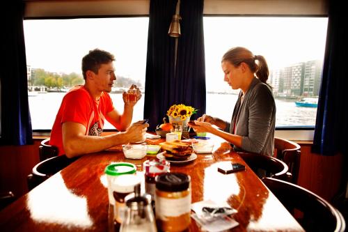 un hombre y una mujer sentados en una mesa comiendo comida en AmicitiA, en Ámsterdam