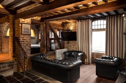 a living room with leather furniture and a brick wall at Appart-Hotel Léopold Liège Centre in Liège