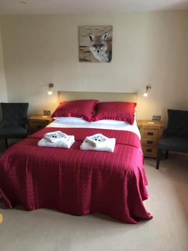 a bedroom with a red bed with two towels on it at Bryn Derwen in Rhayader