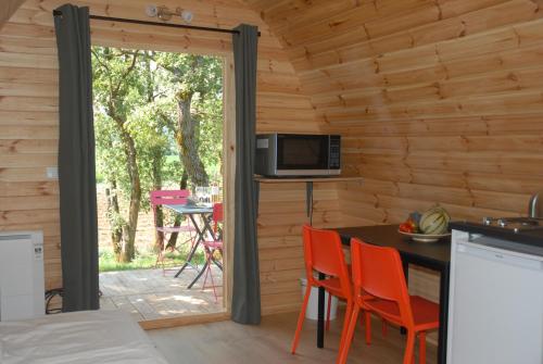 eine Küche mit einem Tisch und Stühlen in einem Blockhaus in der Unterkunft Le Pod de L'Adret in Rians