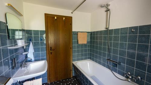 a blue tiled bathroom with a tub and a sink at Haus Kipfen in Sibratsgfäll