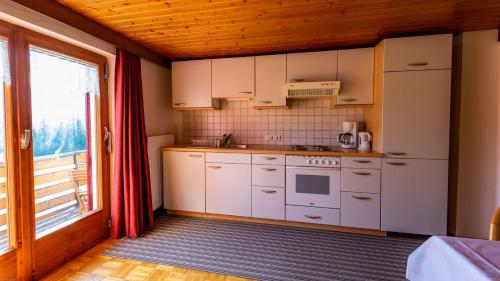 a kitchen with white cabinets and a large window at Haus Kipfen in Sibratsgfäll