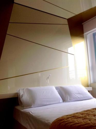 a bedroom with a white bed with a large headboard at Hotel Excelsior in Vasto
