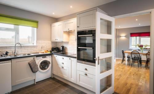a kitchen with white cabinets and a washer and dryer at Hunters Lodge Exeter, Free Parking, Country Views, Great Wi-Fi, Large Garden in Poltimore